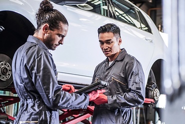 man in workshop infront of a car with brake booster